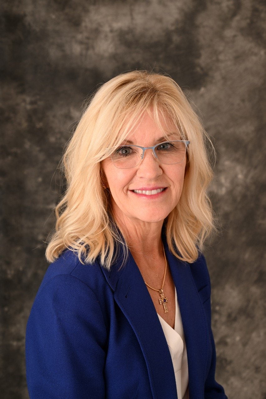Smiling woman in blue blazer and glasses